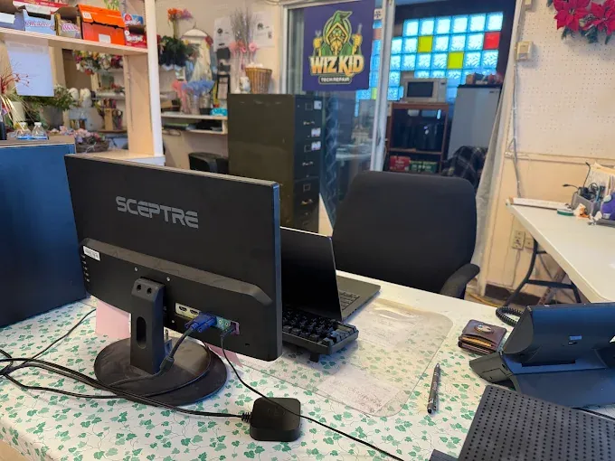 Inside the Wiz Kid Tech Repair shop: workbench, monitor, laptop, and tools ready for repair work